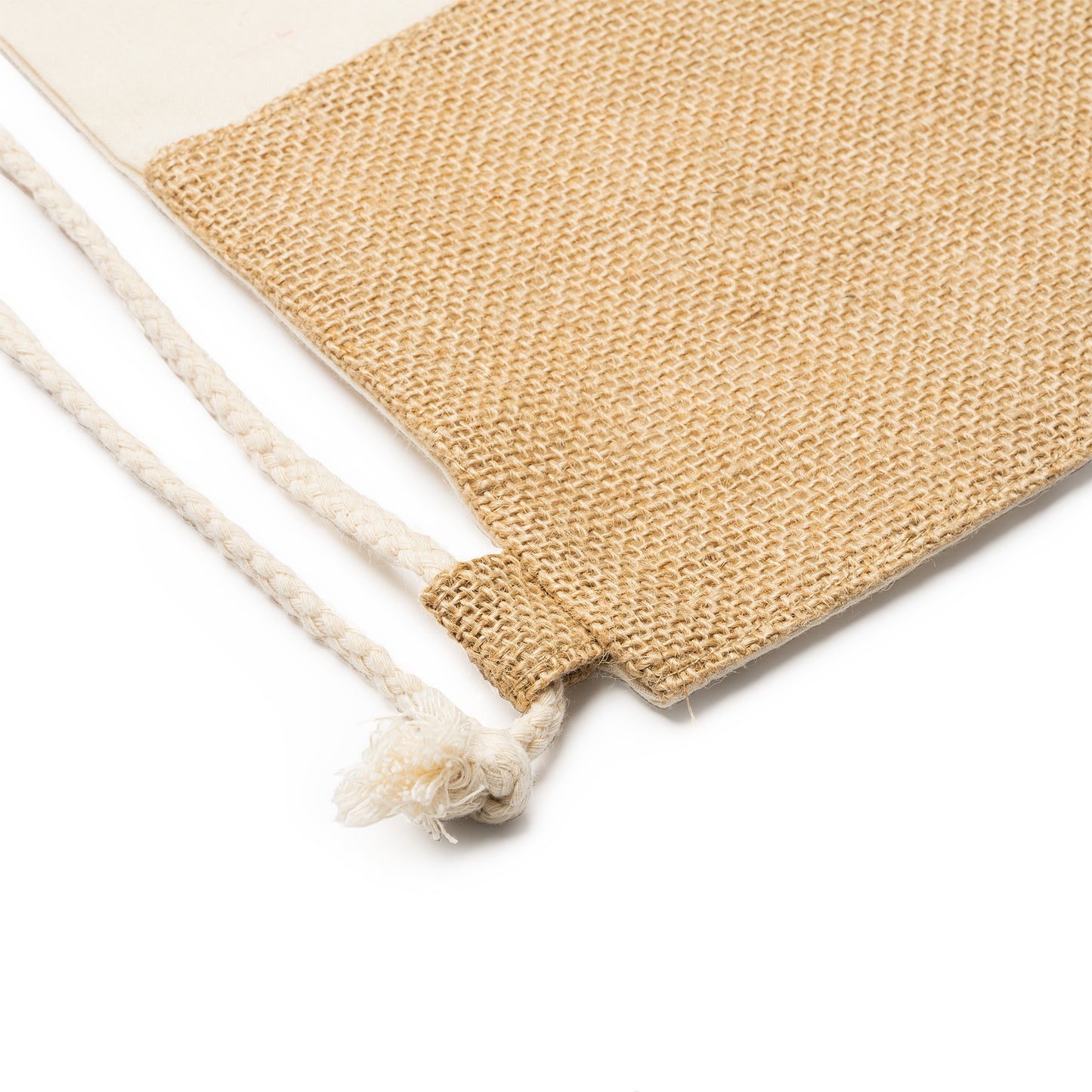 Zaino eco di cotone di 120 g/m² e iuta. Colore naturale. La parte anteriore dello zaino ha una fascia di iuta nella parte inferiore. Lacci cuciti ad entrambi gli angoli inferiori.